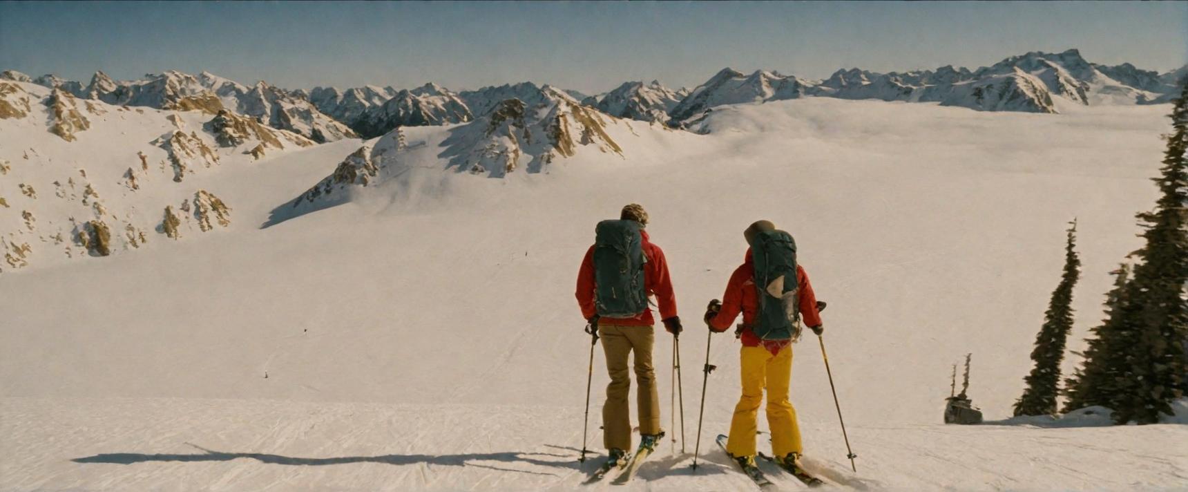  Two skiers standing on a snowy mountain slope with panoramic views of snow-capped peaks and a sea of clouds below, flanked by evergreen trees, under a clear blue sky.